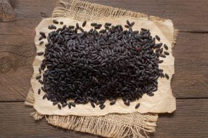 A pile of black rice on a wooden table top view